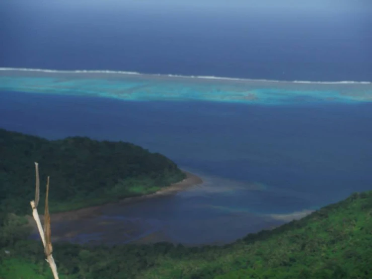 two people standing on top of a mountain overlooking the ocean