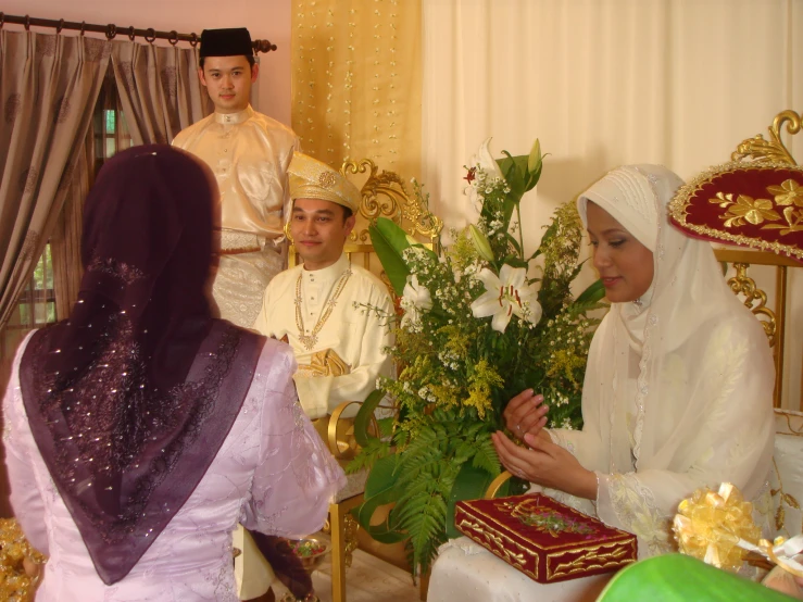 a muslim man and woman talking in a living room with other men
