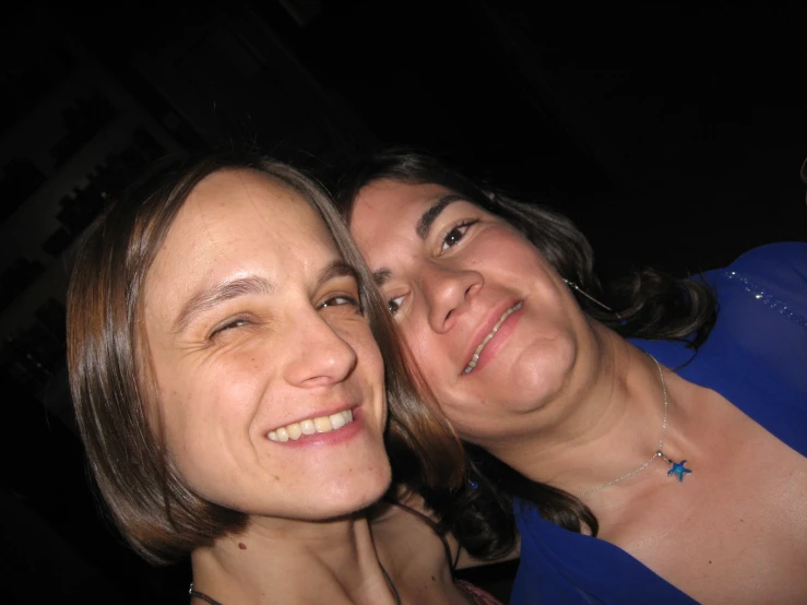 two women are smiling at the camera while wearing jewelry