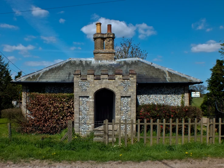a stone building with two chimneys stands next to a fence