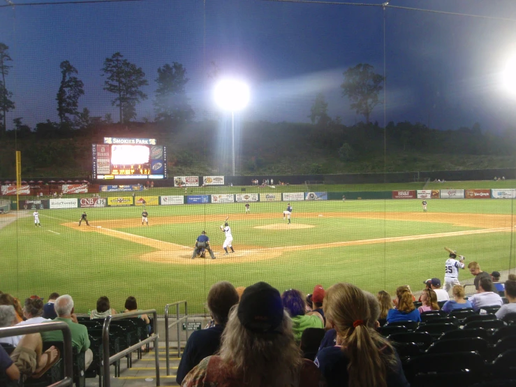 a baseball game in progress at night time with fans