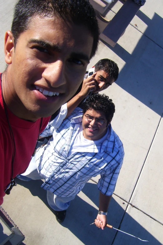 three men posing with cell phones on their heads