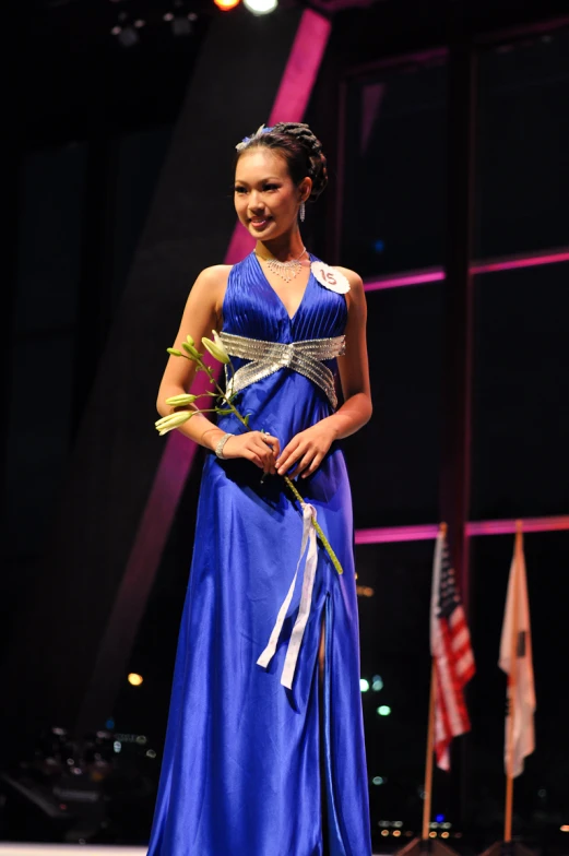 a woman in a blue dress is standing on a stage