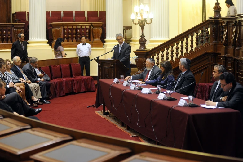 a group of people sitting at tables with microphones and papers