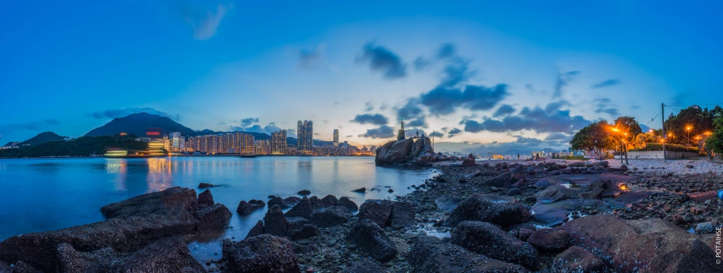 view of an ocean from the shoreline of a city at twilight