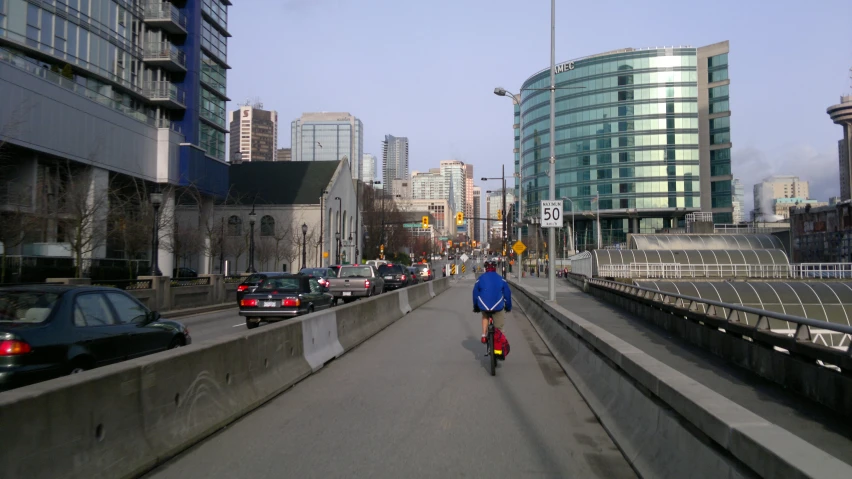 man riding a bike across a bridge in the city