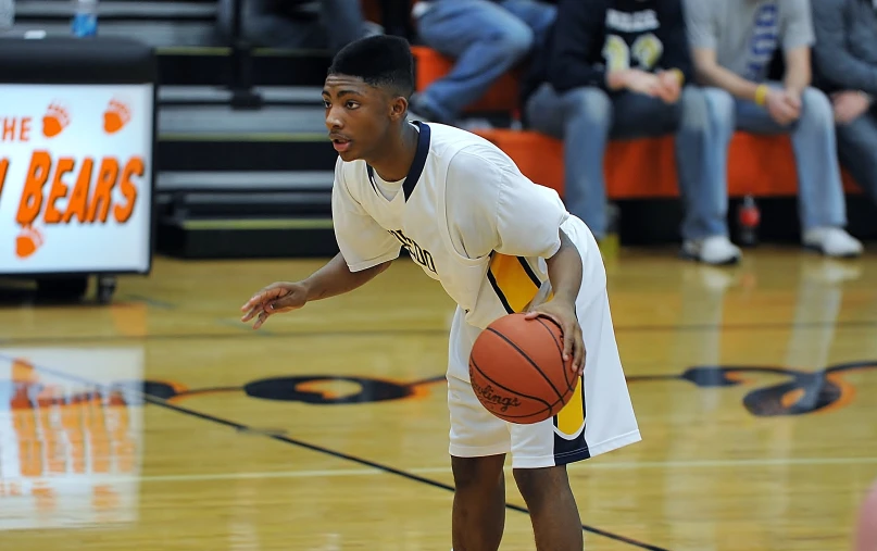 a young man holding a basketball while standing on a court