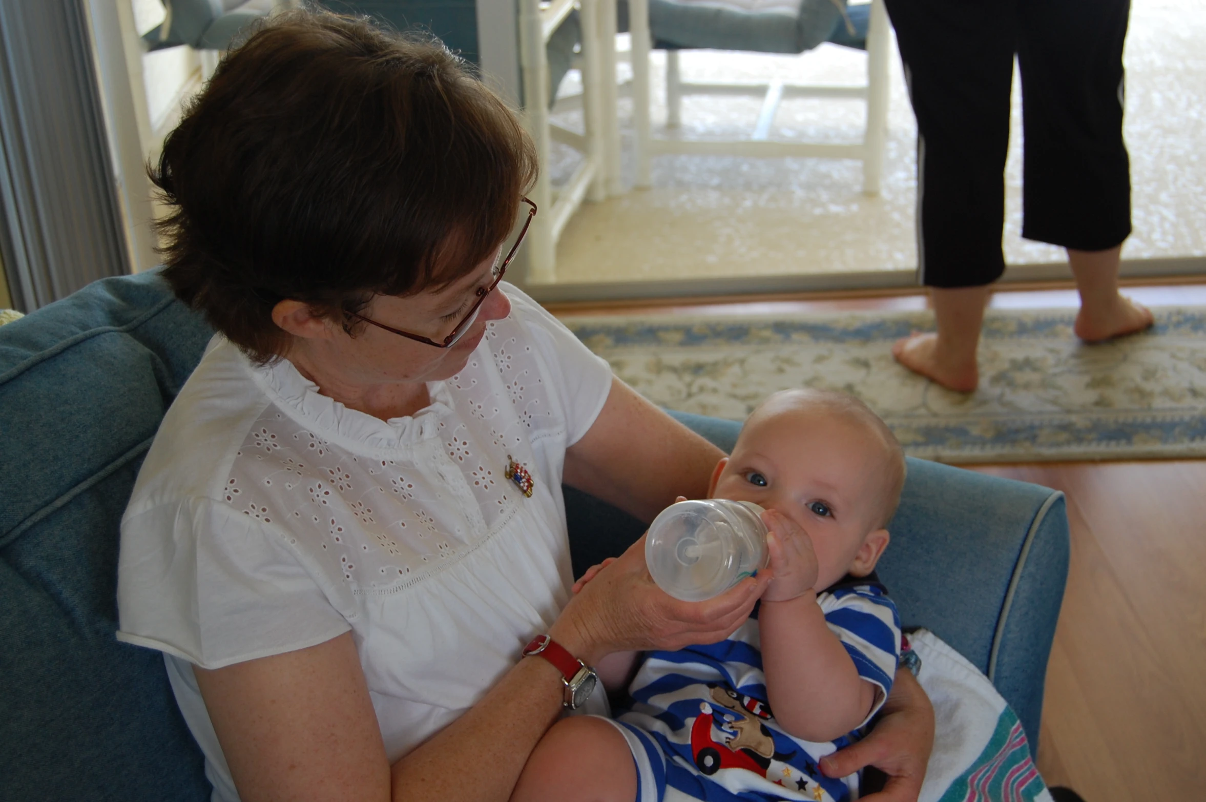 a woman sitting in a chair feeding a baby with a bottle