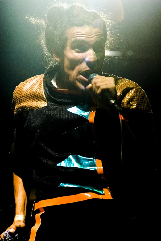 a man holds a microphone up in a spotlight