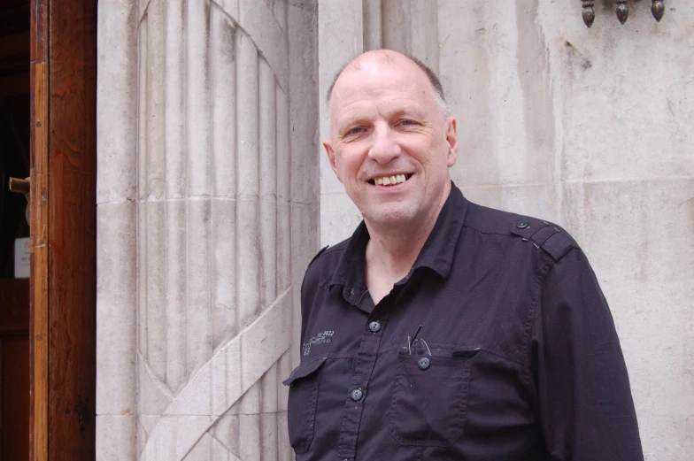 a man in black shirt and a stone building