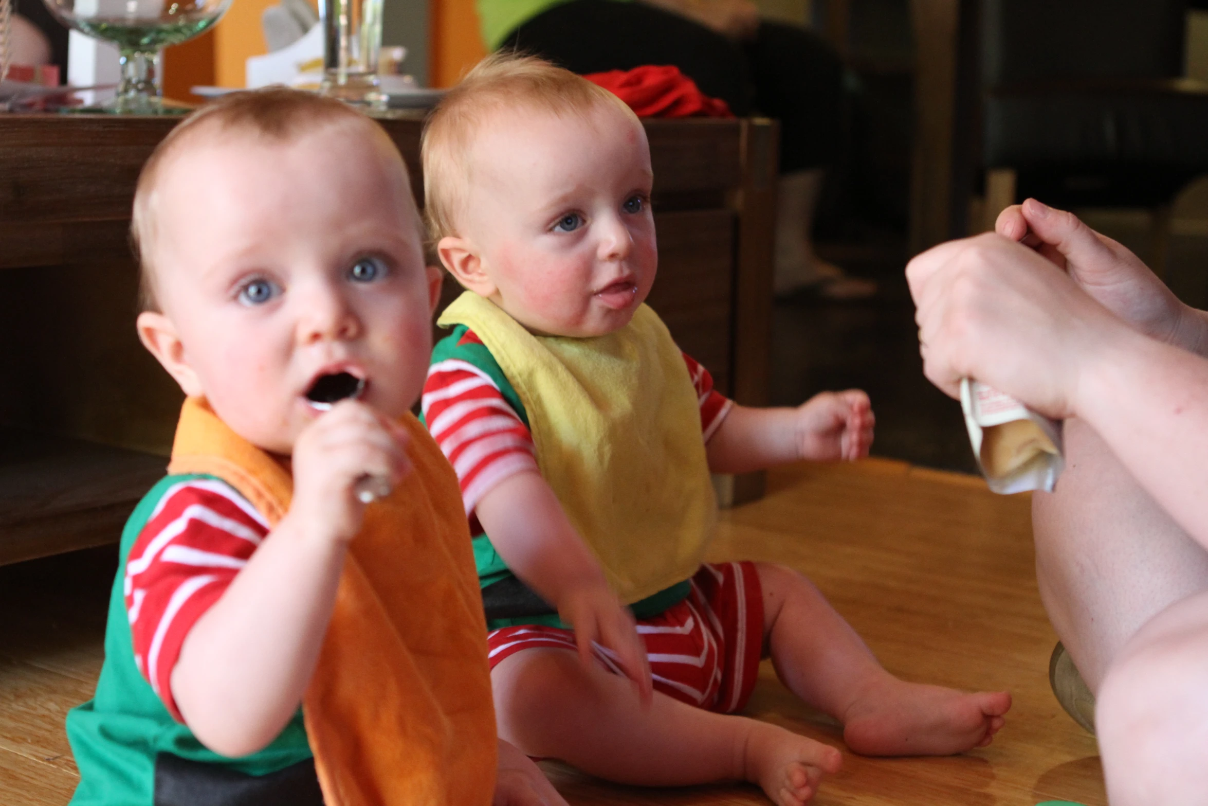 two baby boys sit next to each other, brushing their teeth