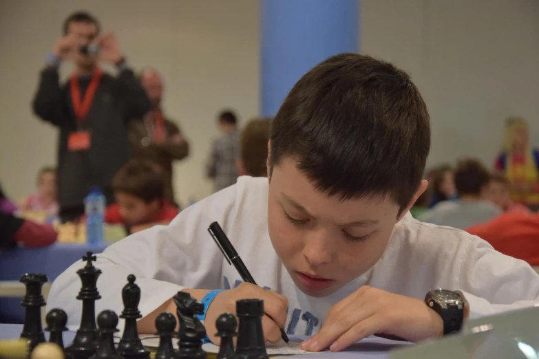  writing on paper while sitting at table with chess set and game