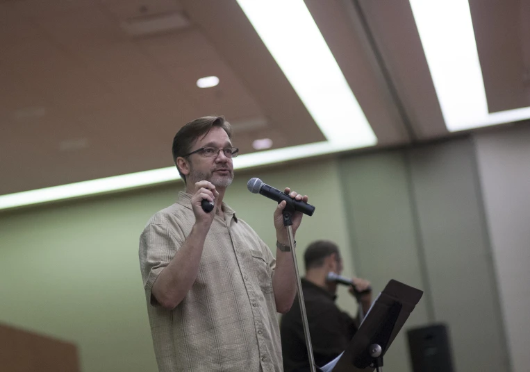 man talking into a microphone with band mates standing around him