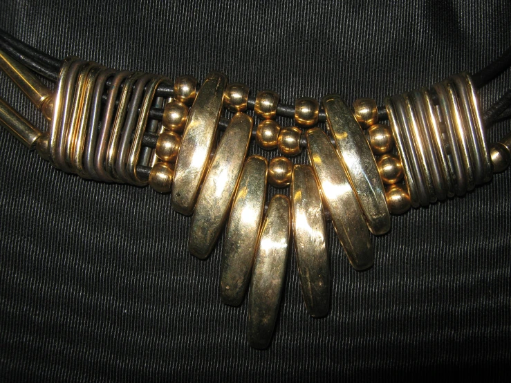 a necklace with gold rings and beads on a black background