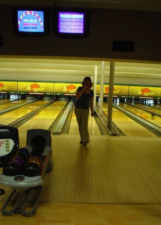 a woman is walking around in an indoor bowling alley