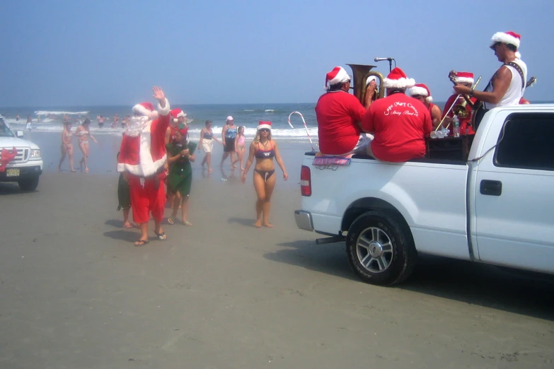 several people dressed in santa claus suits at the beach