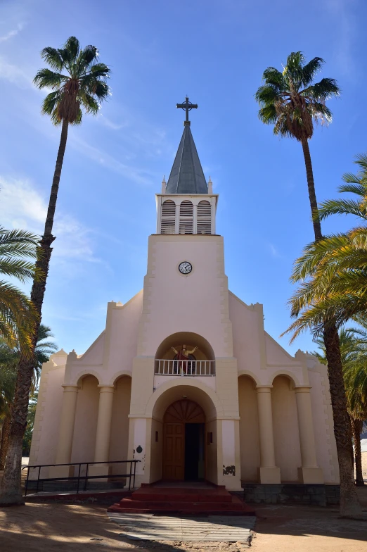 a palm tree and blue sky behind an old church