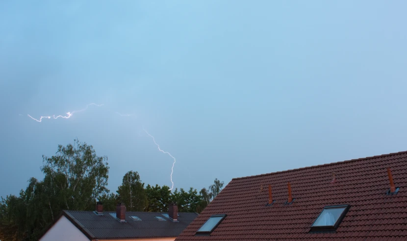 two lightning strikes over houses on a cloudy day