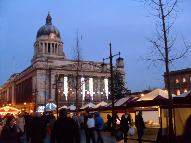 people walking around an outdoor market near an old building