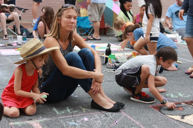 children and adults play with chalk drawings on pavement