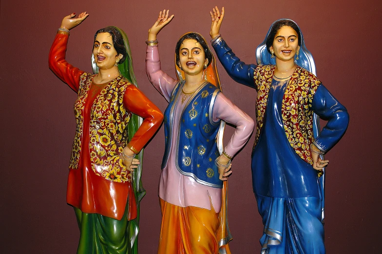 three statues in brightly colored outfits are posed