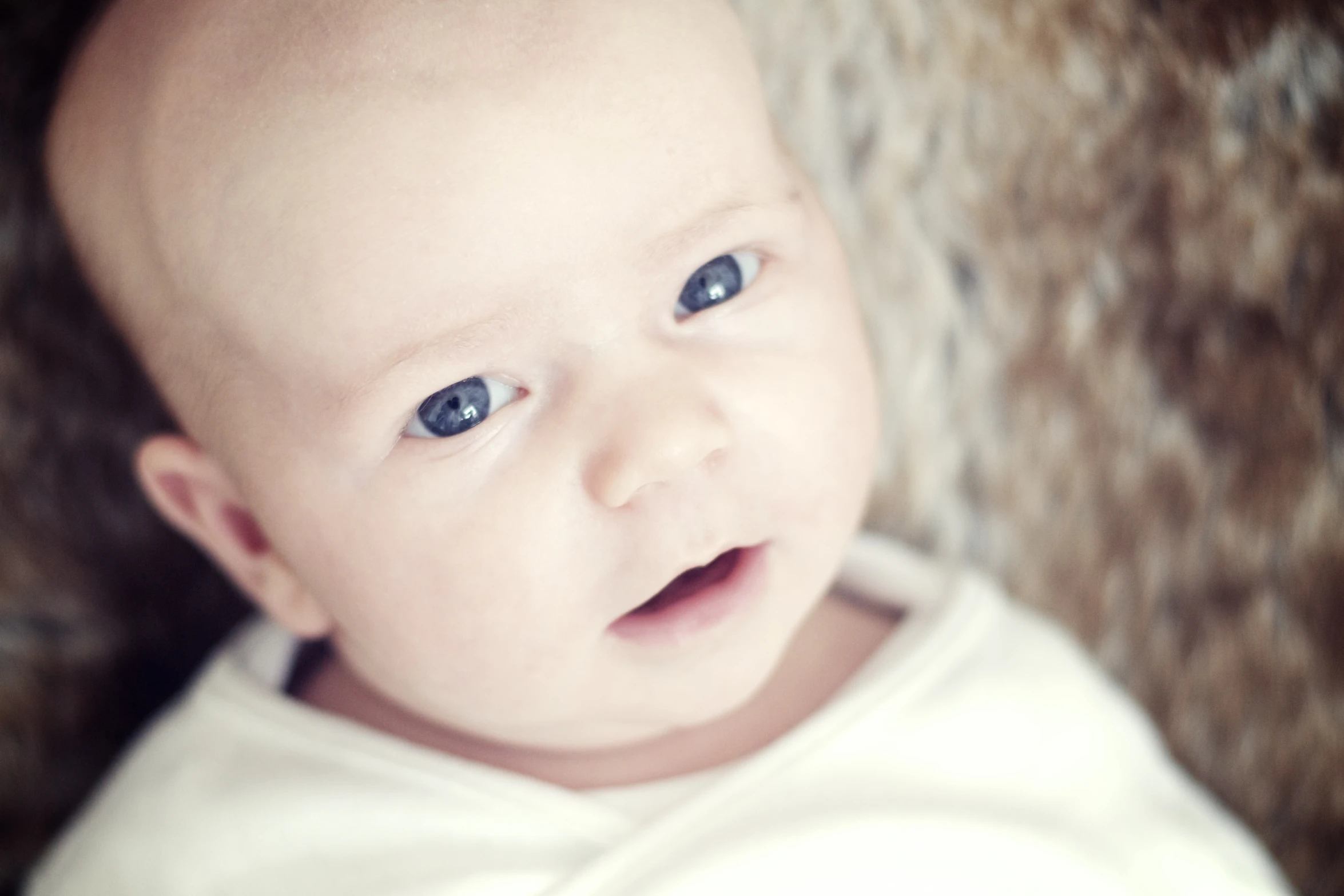 a baby that is laying down with blue eyes