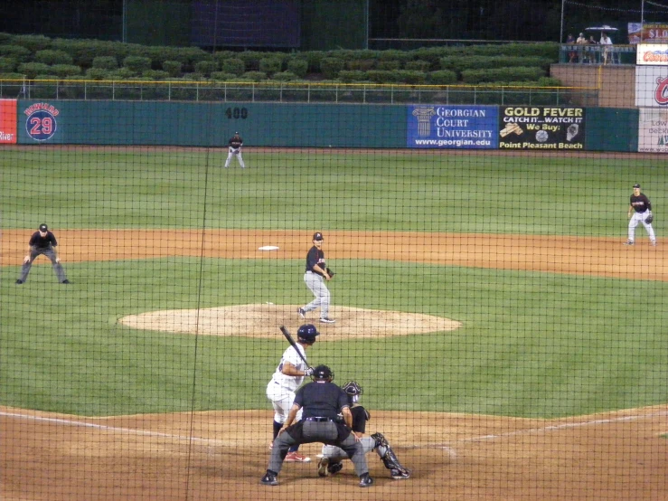 baseball players standing at home plate with a pitch