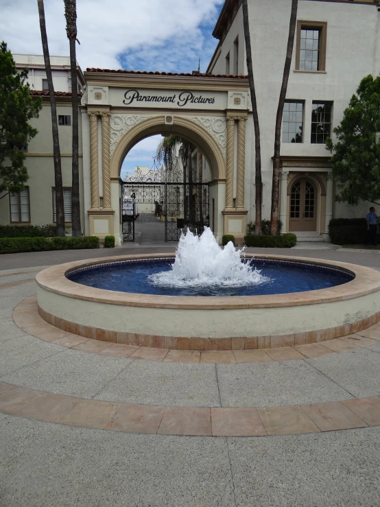 a fountain in front of a large building with a gate behind it