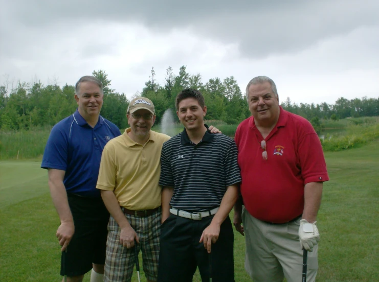 four men posing for a po with a fountain in the background