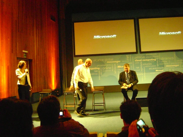 three people in front of a screen in a building