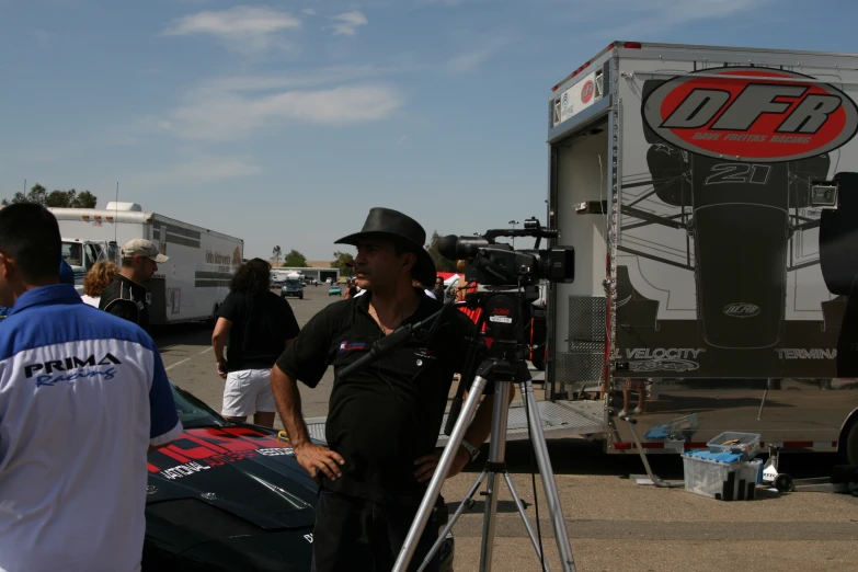 a tv reporter standing next to a car at a race