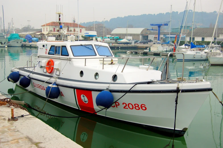 a white boat sits in the water near other boats