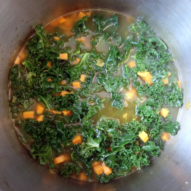 a large metal bowl filled with broccoli soup