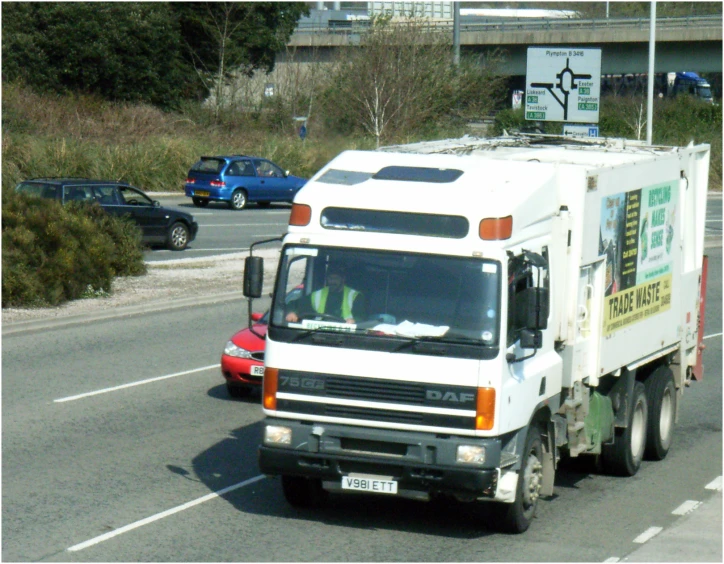 a white utility truck in the street next to a red car