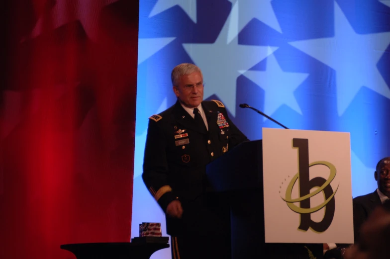 a man in uniform standing at a podium on stage