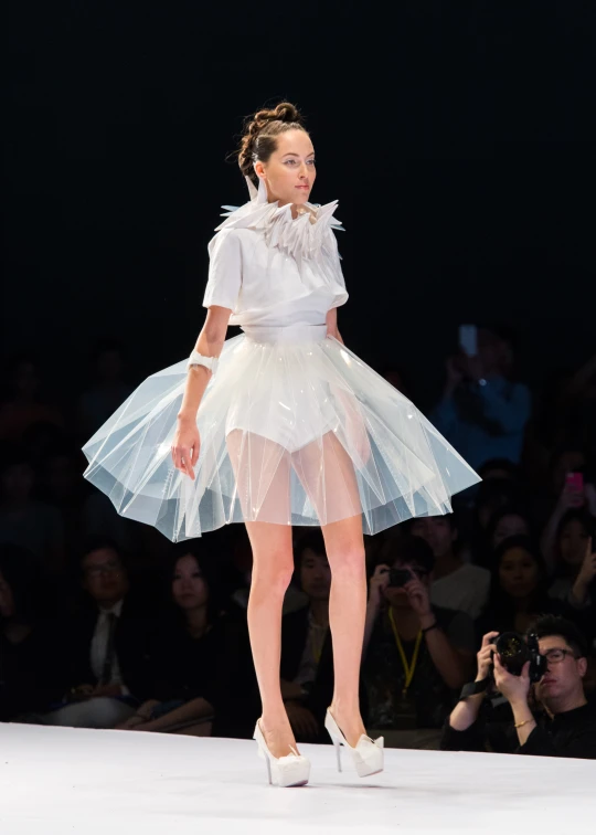 the model wears white dresses on a runway