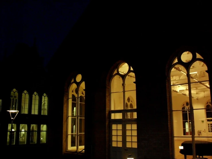 three windows are glowing at night, and there is a black background