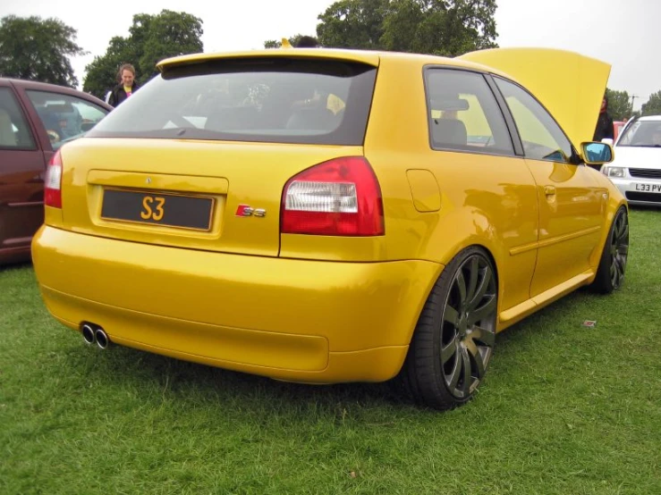 the back of a yellow car at an automobile show