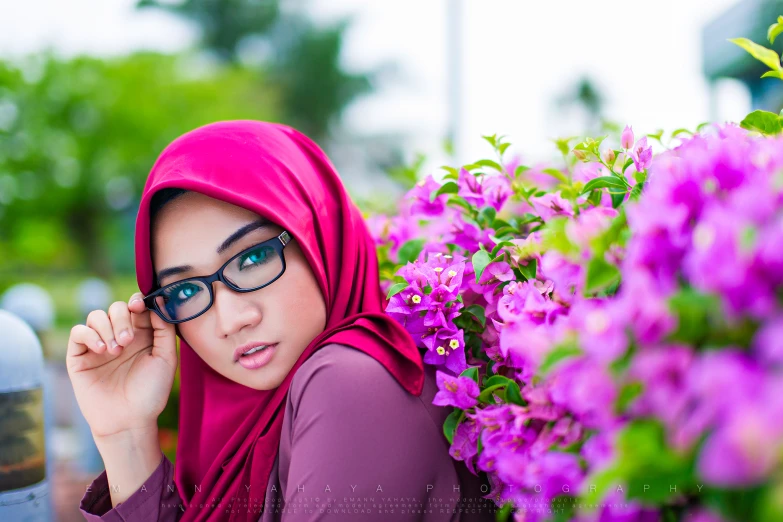 a girl with a pink hijab in front of flowers