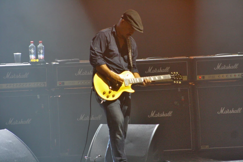 a man playing a yellow guitar on a stage