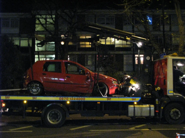 a car is on a tow truck after being pulled away from a building