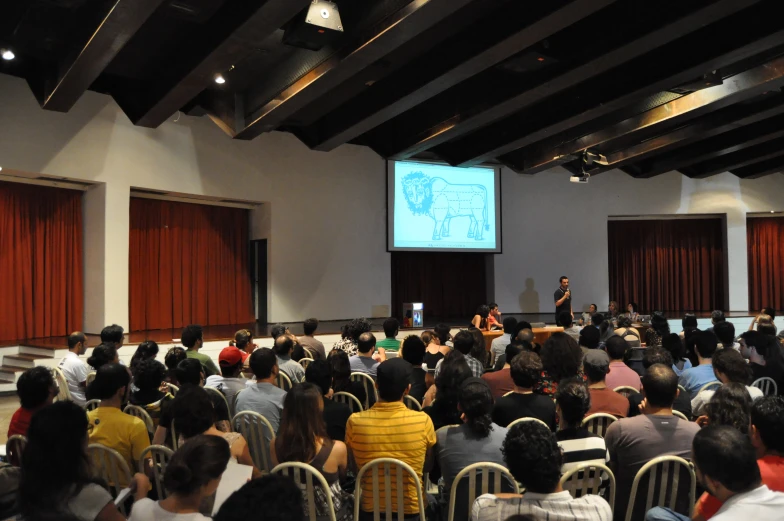 people sitting in a auditorium watching a presentation