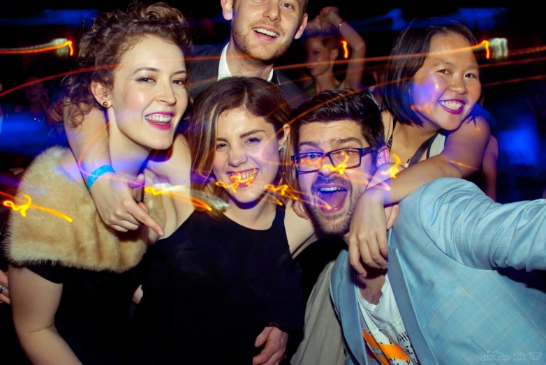 a group of people smiling together with glowing lights in the background