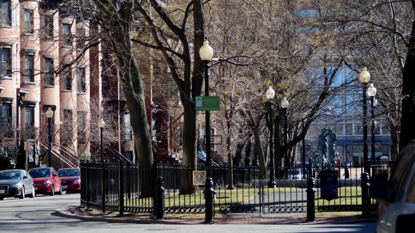 several cars are parked along the street behind a fence