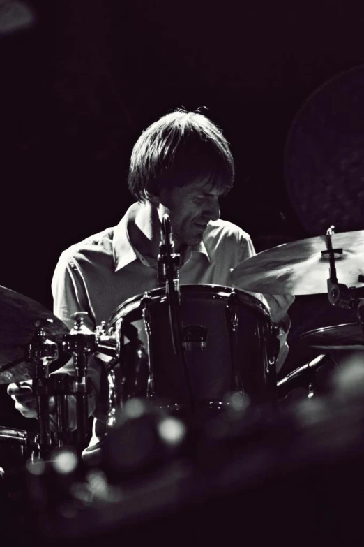 man playing on drums in black and white
