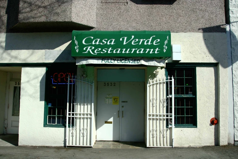 a green and white restaurant has an arched glass front entrance