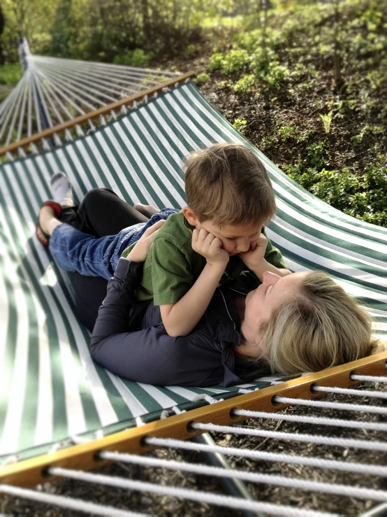 a  and woman lying on a hammock with their dog