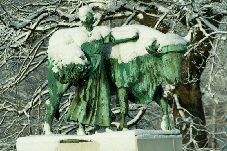 two marble statues are shown in front of a snow covered tree
