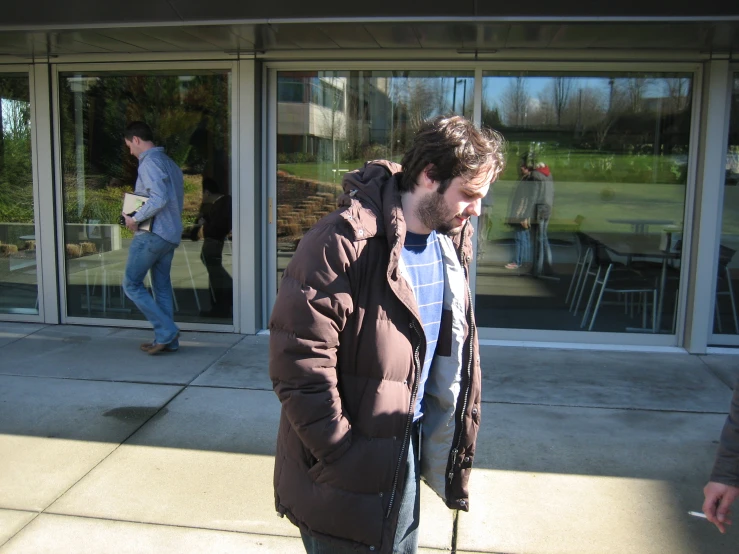 a young man wearing a parka and looking at his cell phone