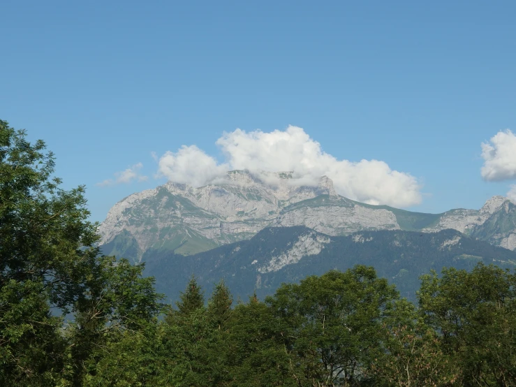 trees and mountains under a blue sky with clouds